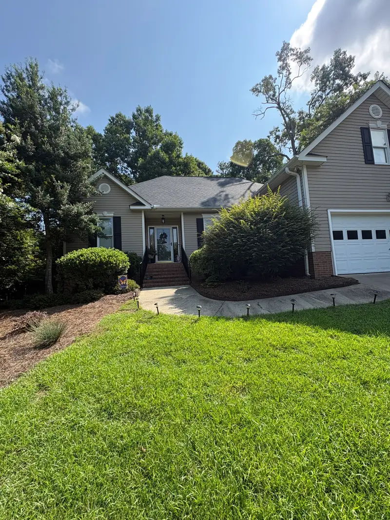 Mowed lawn and shaped shrubs framing a front walkway