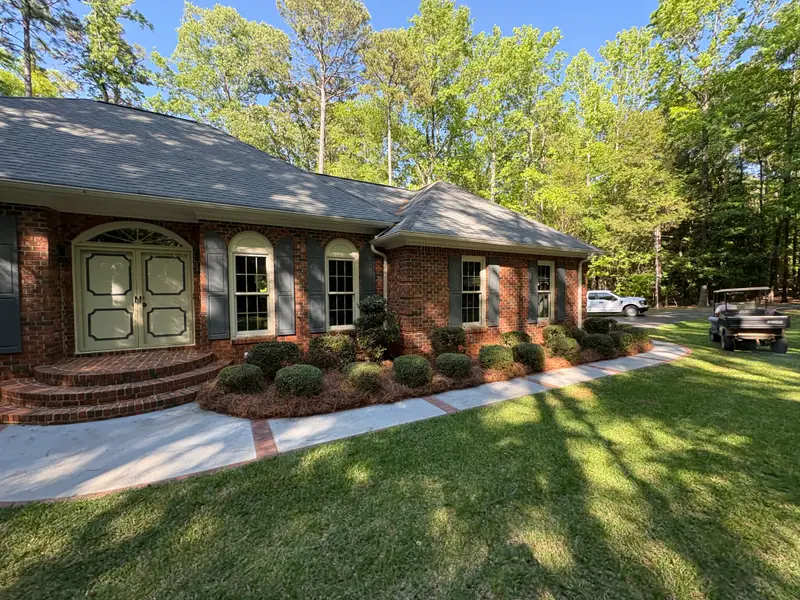 Fresh mulch and rounded shrubs along a brick ranch home