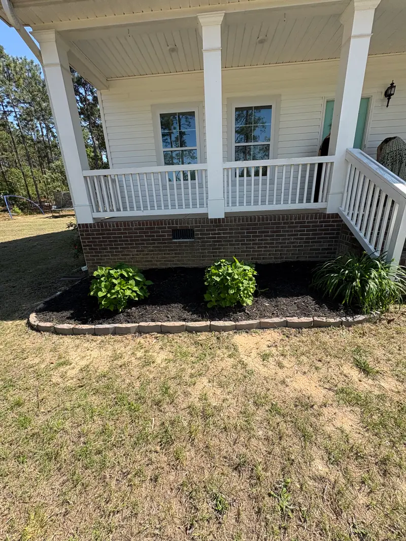 New plantings in a fresh mulch bed beside a front porch