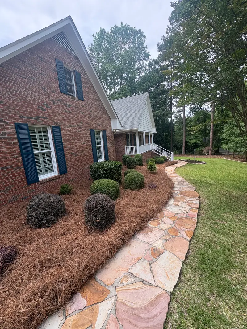 Stone-bordered mulch bed with fresh plantings at a front porch