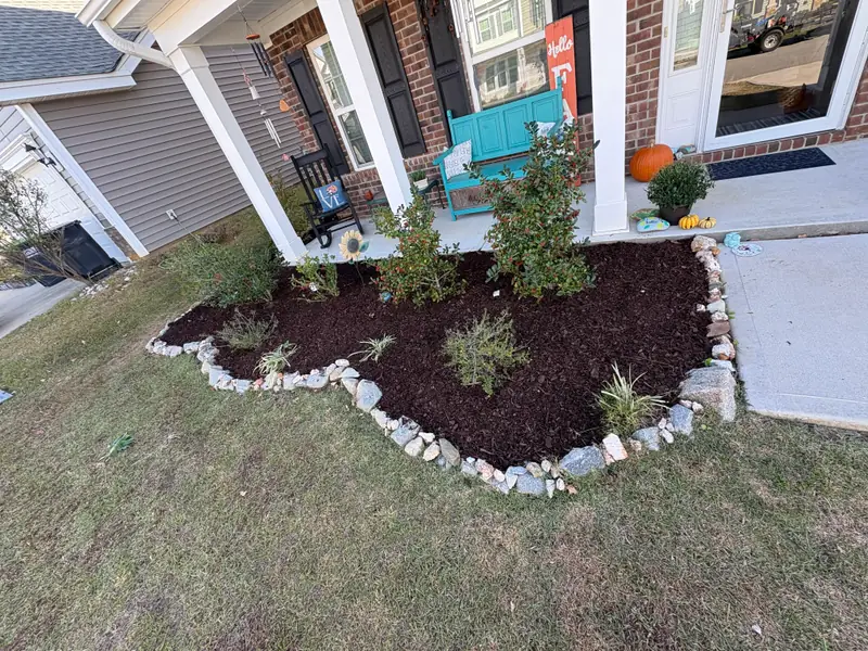 Mulch bed edged with natural stone beside a front porch