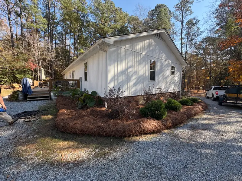 Pine straw bed and trimmed shrubs beside a gravel drive