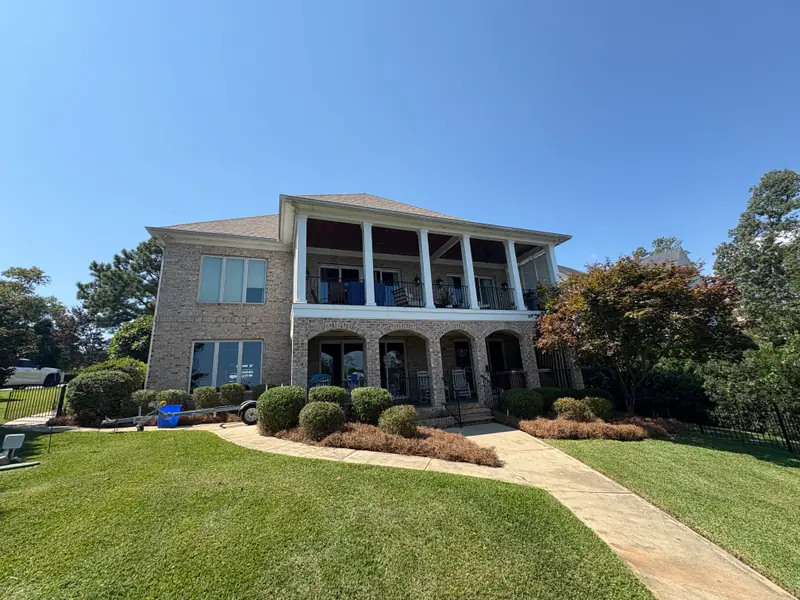 Trimmed shrubs and pine straw beds at a two-story brick home