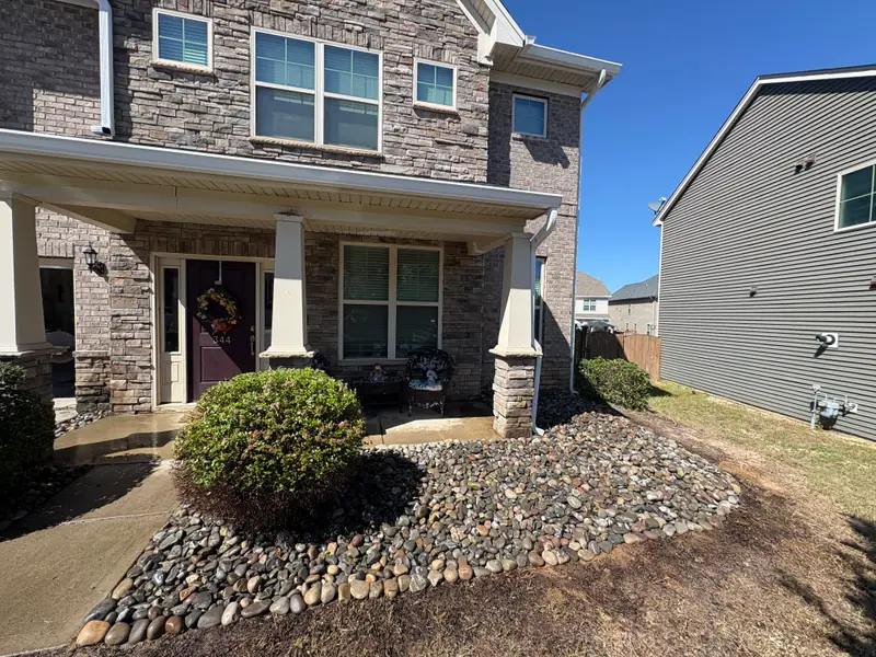 River rock bed and shrubs at a stone-front townhome