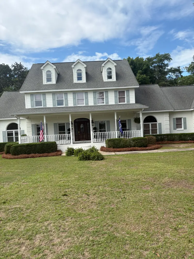 Striped lawn in front of a white colonial home