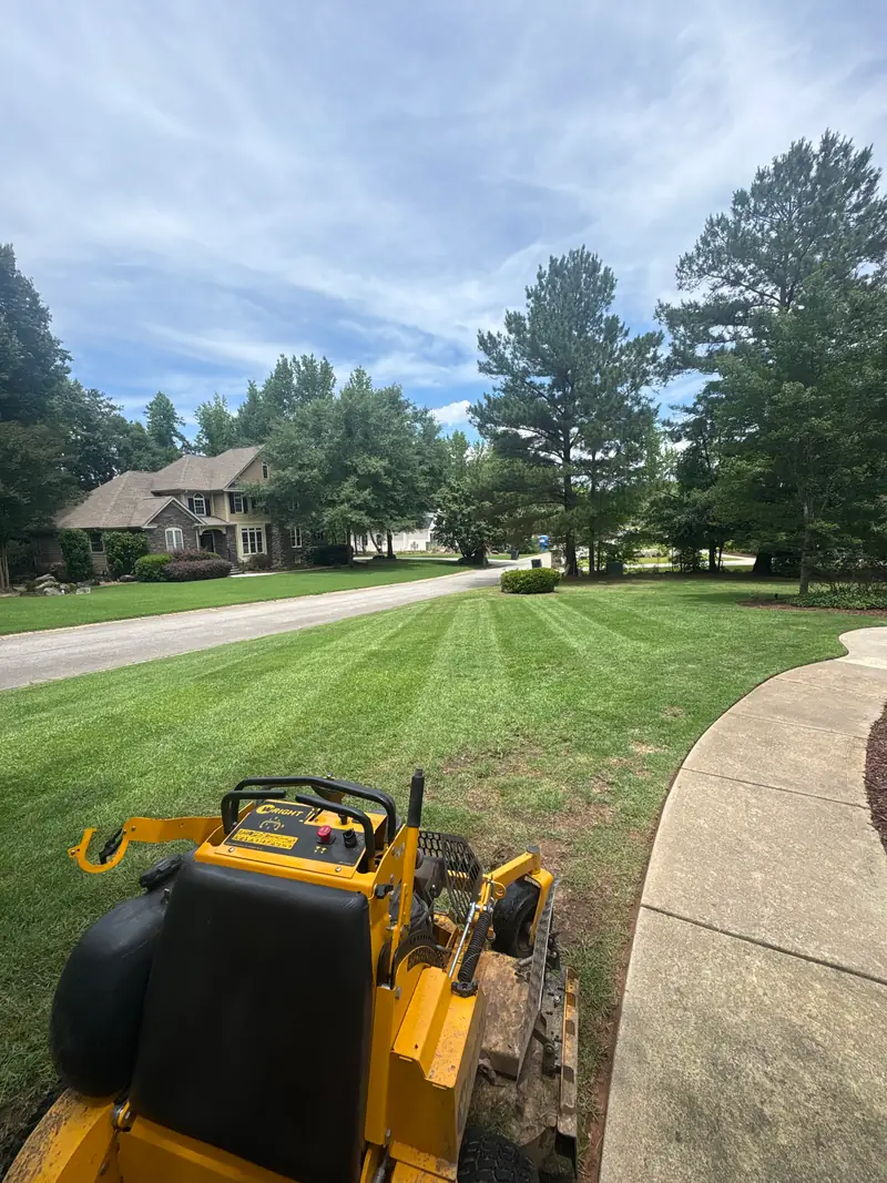 Zero-turn mower finishing a striped front lawn