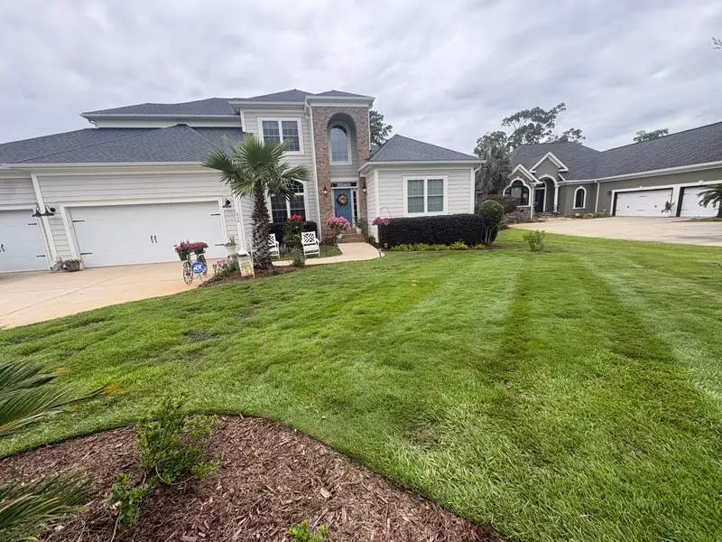Striped lawn and mulch beds at a stucco home entry