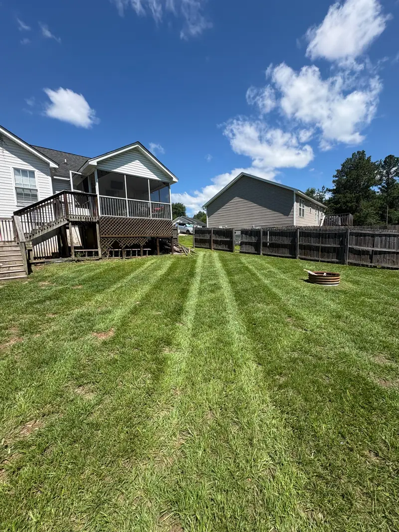 Striped mowing in a back yard beside a screened porch